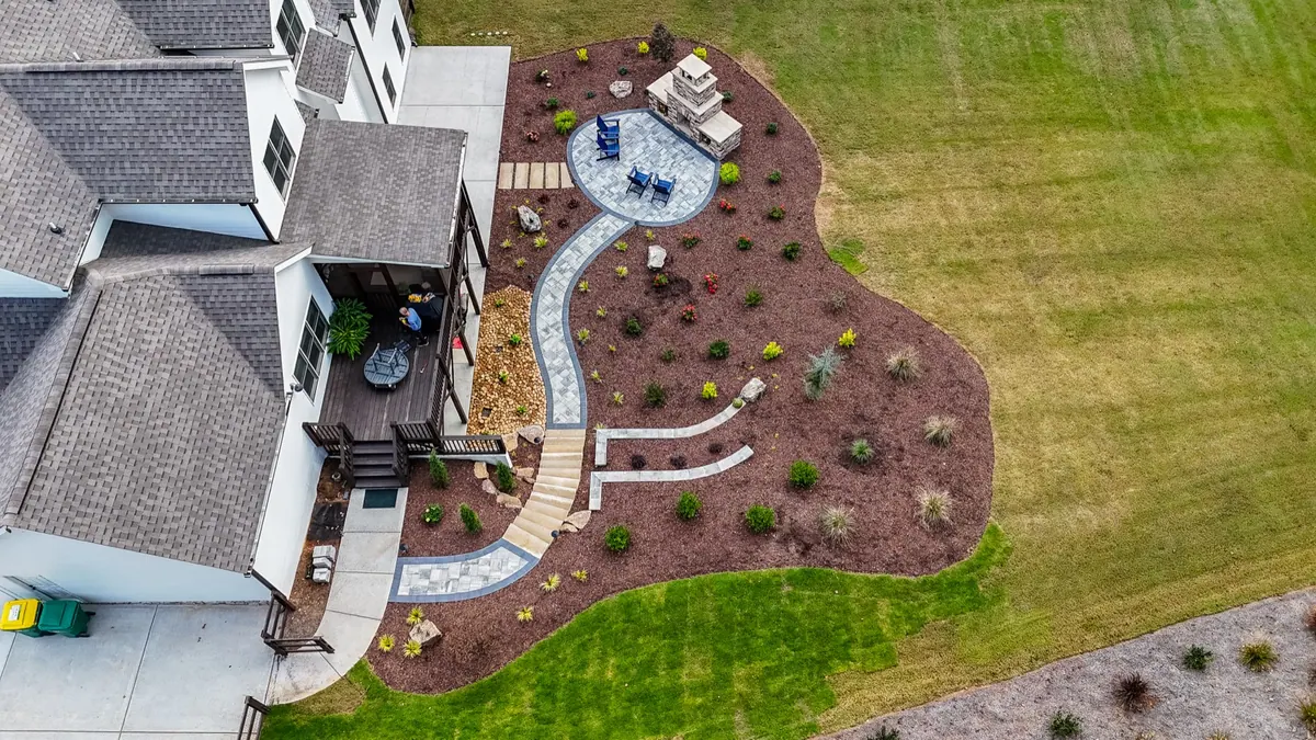 Drone view of the completed Ball Ground backyard: path, patio, fireplace, and new plantings