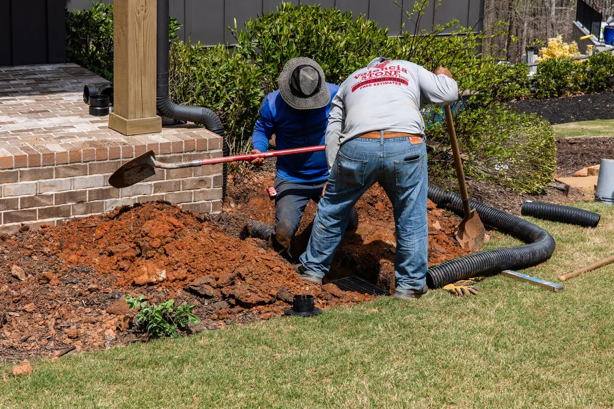 GreenTree crew installing buried corrugated drain lines along the foundation beds during the Blueberry Ridge build in Milton
