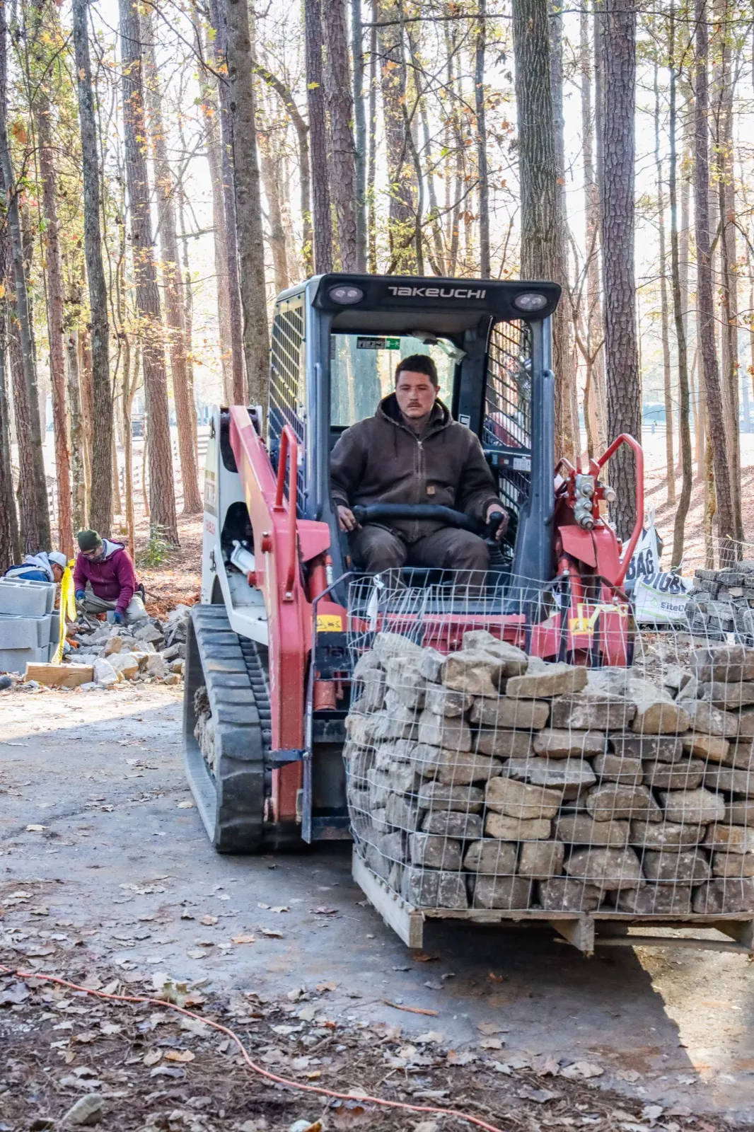 GreenTree crew member moving stacked stone on a job site