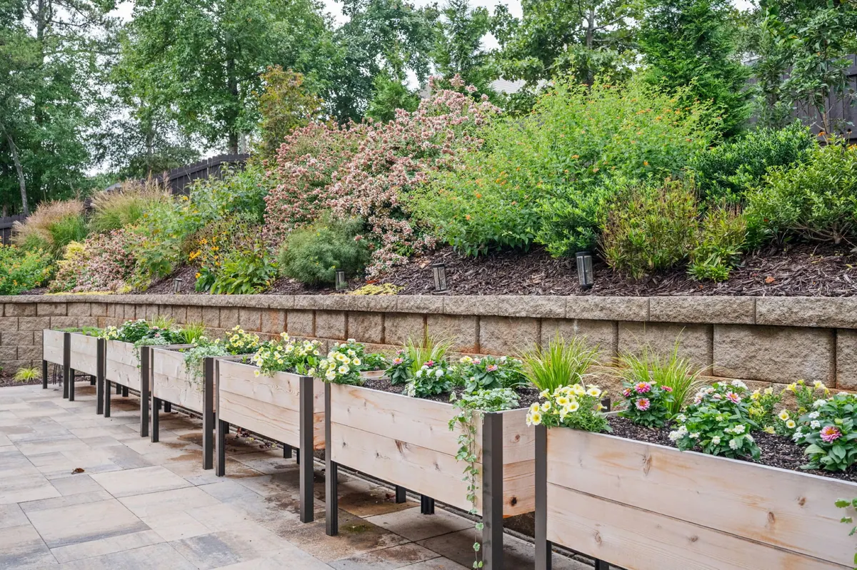 Raised wooden planters beside a paver patio and terraced planting beds