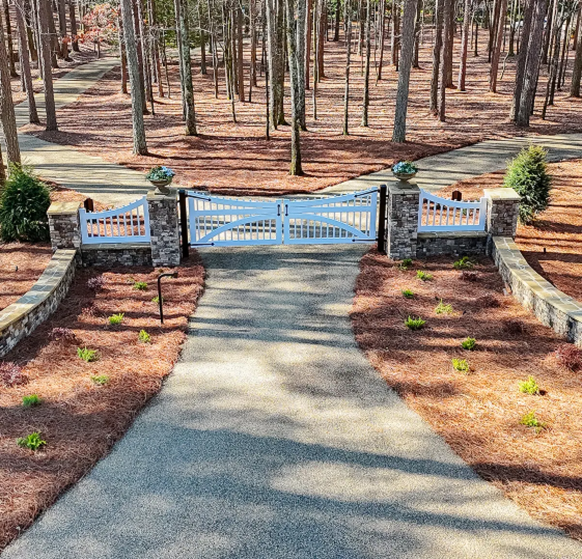 Curved stacked-stone entrance walls flanking a fresh driveway apron