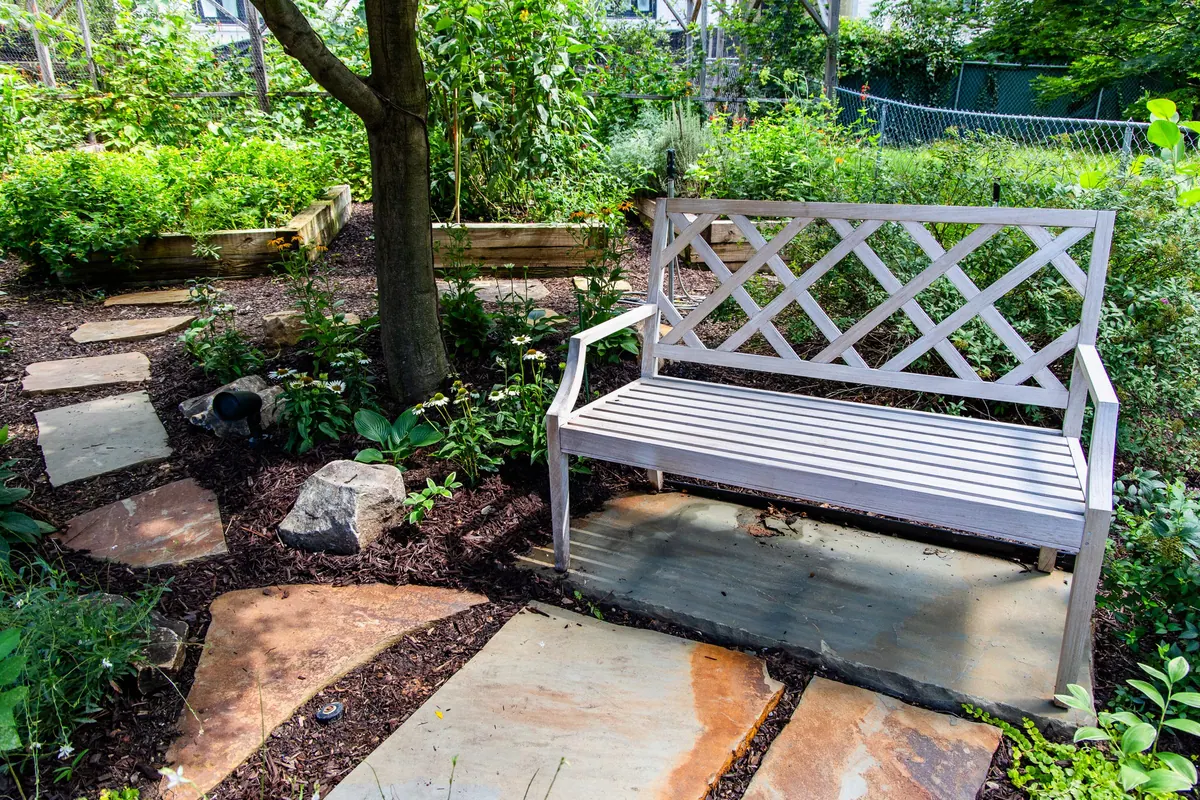 White garden bench in a planted nook of an established Atlanta garden by GreenTree Landscapes