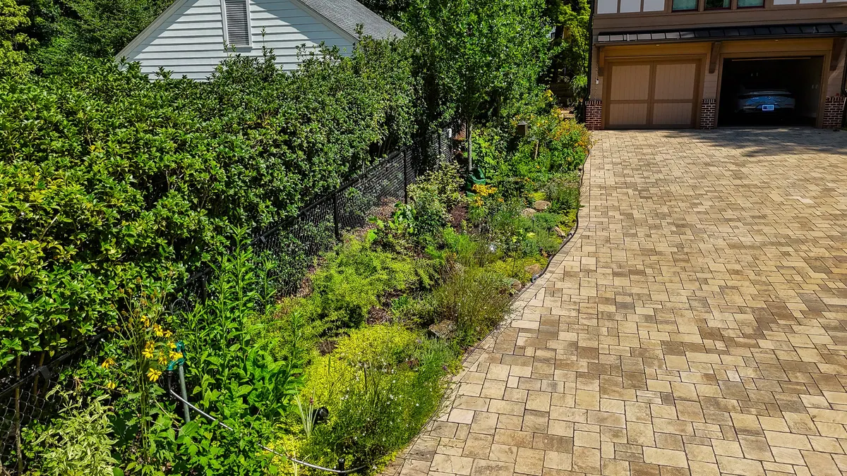 Paver driveway entrance framed by lush planting beds and landscape lighting on a GreenTree build