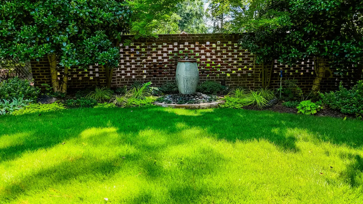 Urn fountain against a pierced-brick garden wall over a manicured lawn at the Eulalia Road garden in Atlanta