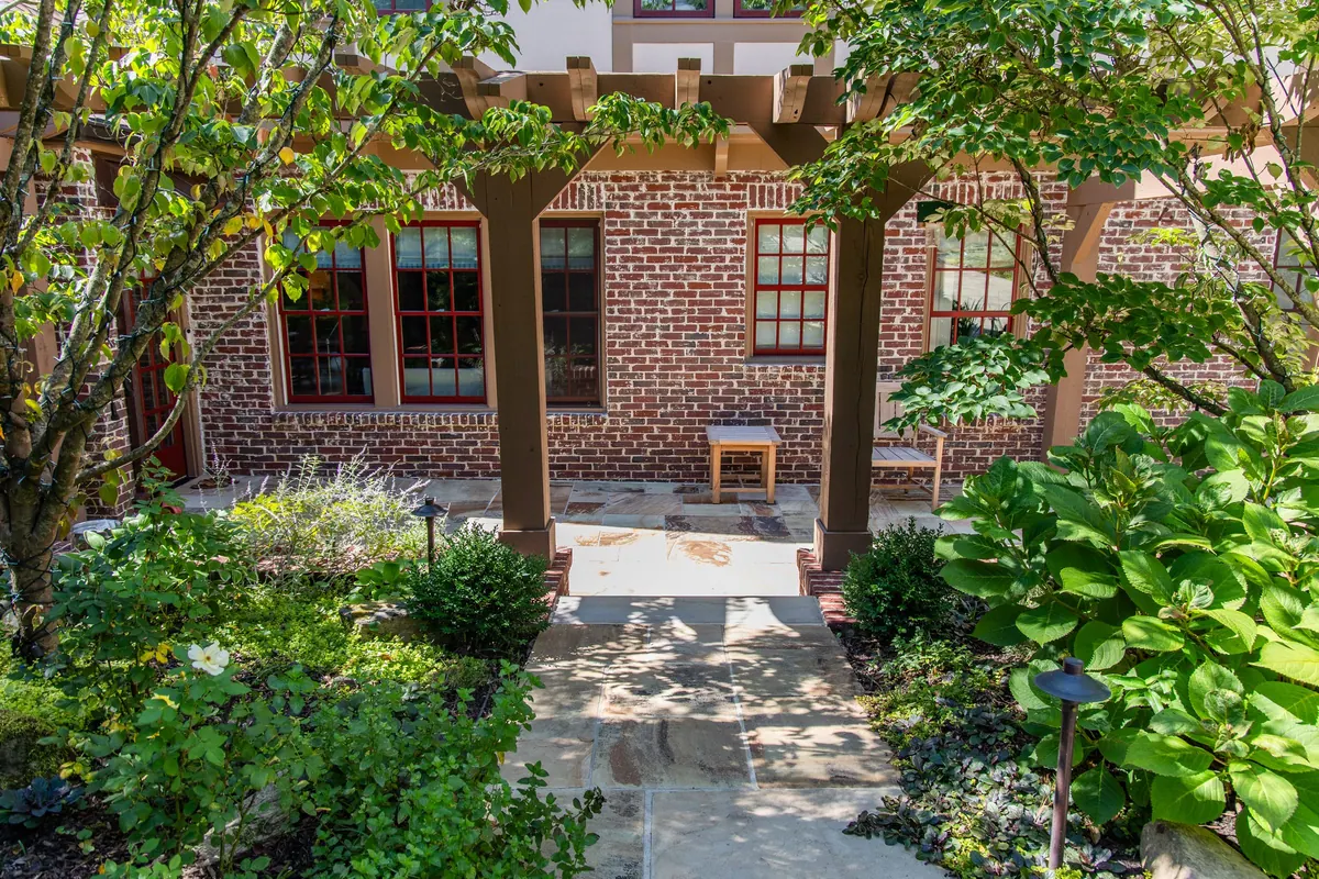 Pergola-shaded stone terrace against the Tudor brick facade