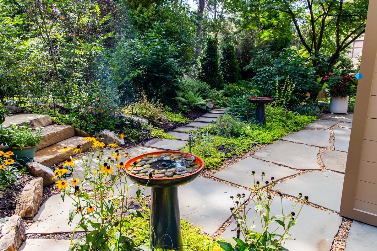 Birdbath fountain among black-eyed susans and coneflowers along the flagstone path