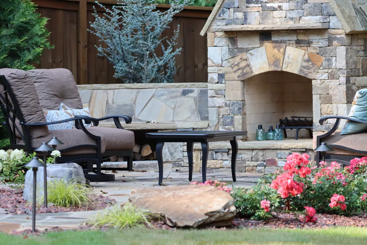 A GreenTree backyard with stone patios, an outdoor fireplace, and lush landscaping