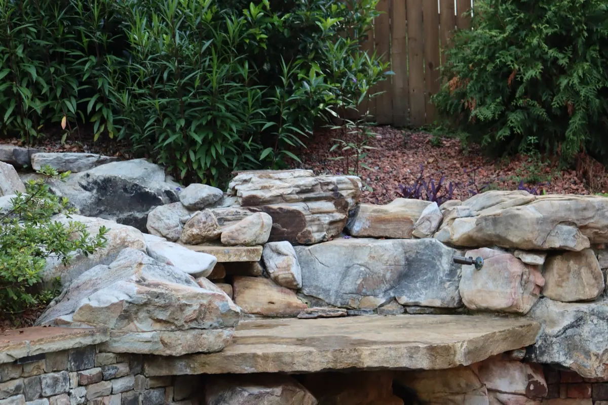 Stacked boulder retaining wall with fresh plantings