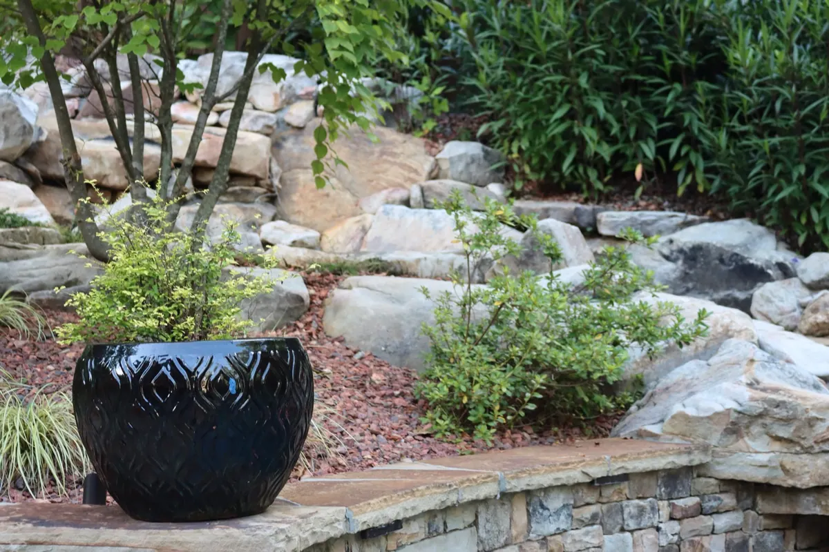 Boulder-edged planting beds with ornamental grasses and a decorative planter