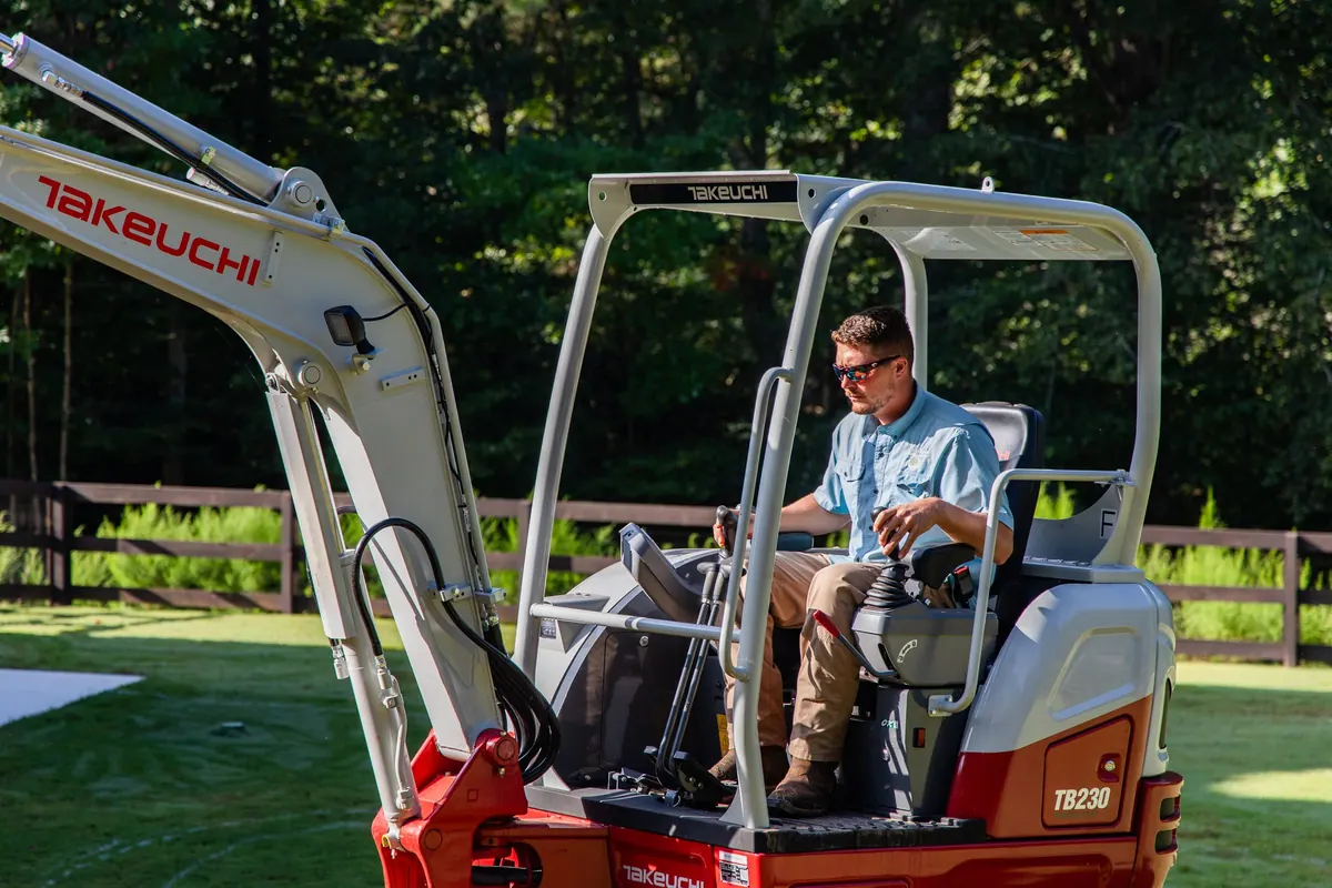 Jay Wilkinson, owner of GreenTree Landscapes, at the controls of a Takeuchi excavator on a customer's backyard build.