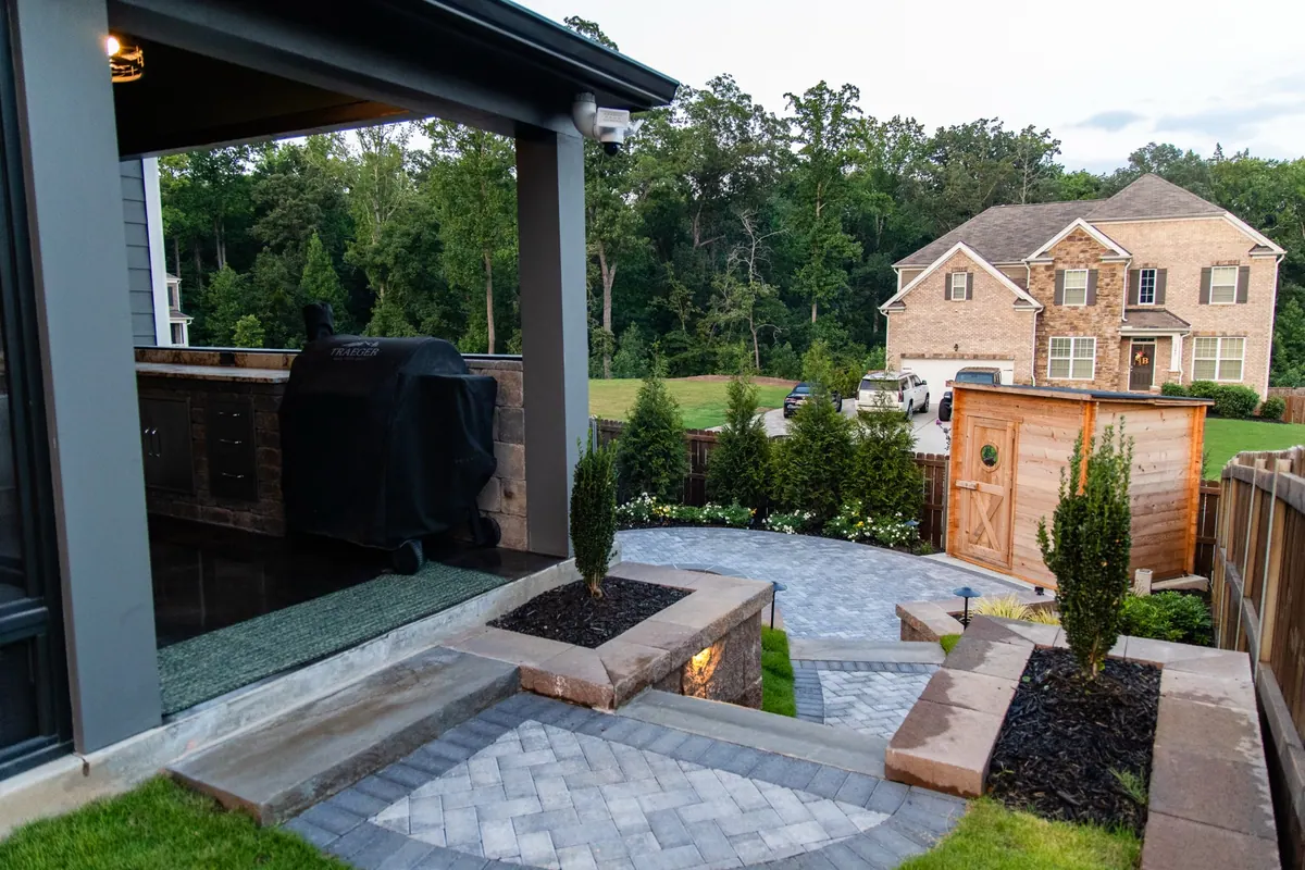 Covered patio, paver walkway, and planting beds at dusk at the Fulton Estate