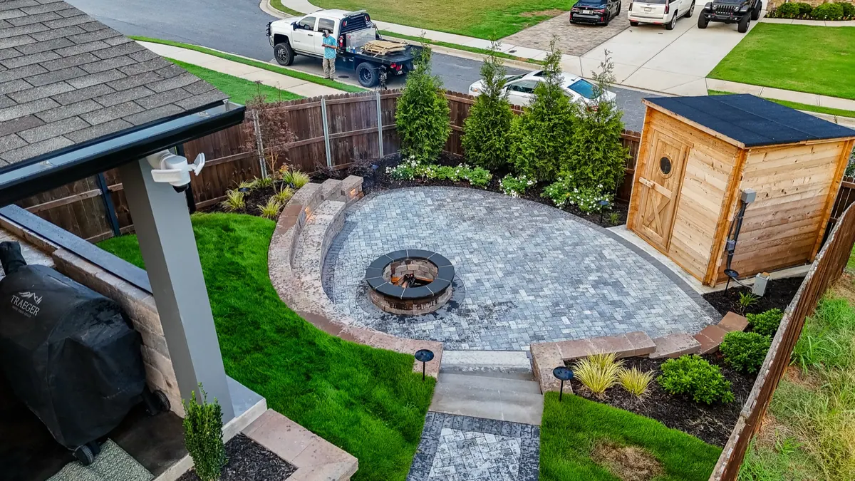 Aerial view of a fire pit patio, planting, and cedar sauna on a complete backyard build