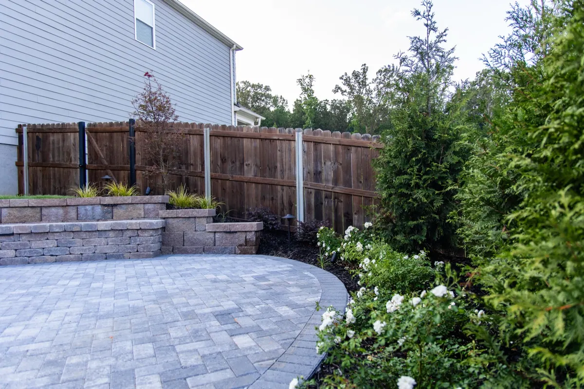 Curved paver patio, stone retaining wall, and fence at the Fulton Estate