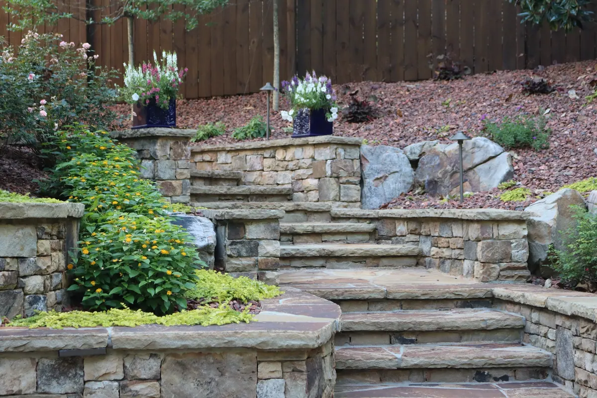 Stacked stone steps, boulder walls, and planting beds built by GreenTree Landscapes