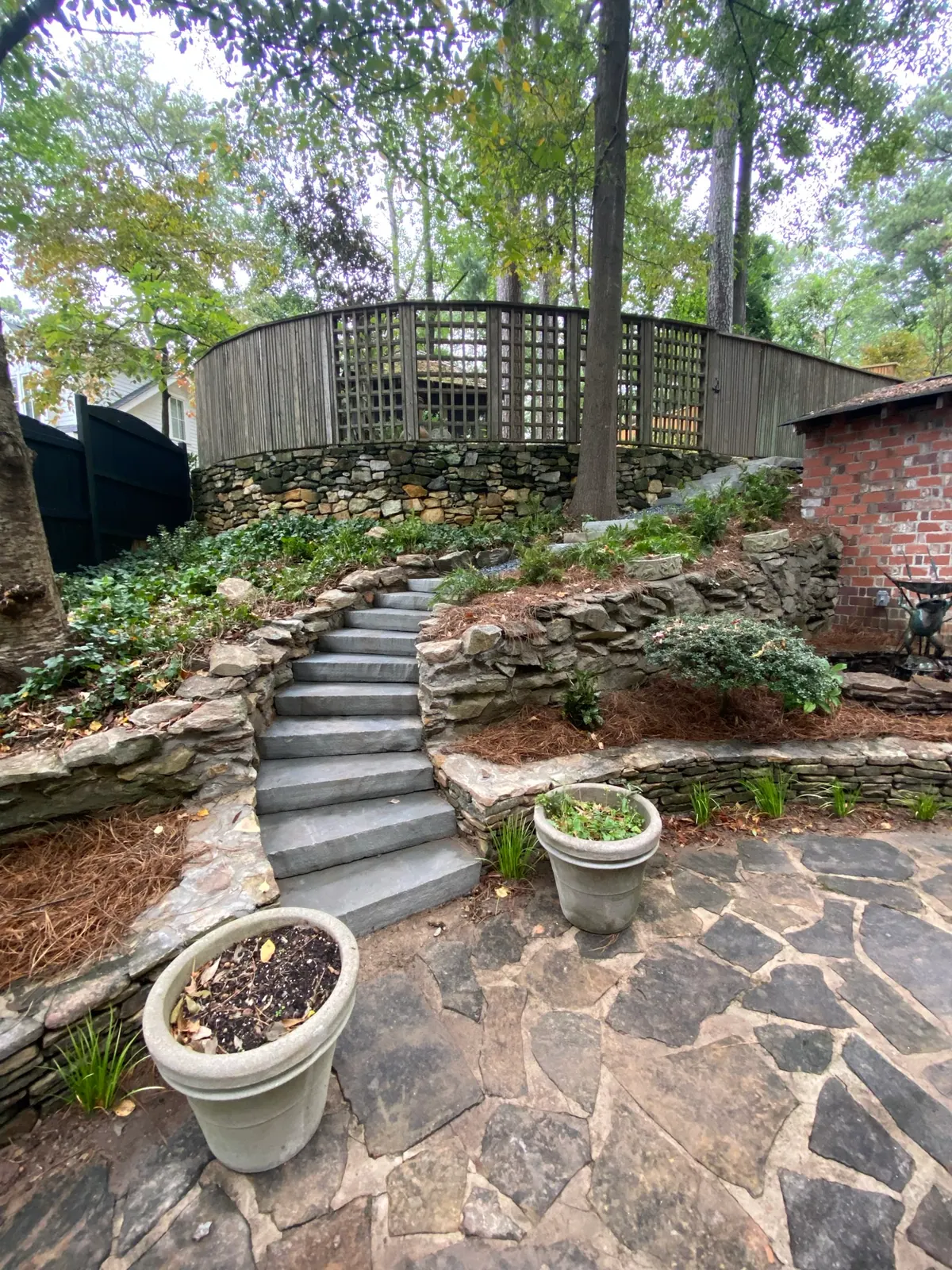 Hillside flagstone terrace with stone steps and terraced planting by GreenTree Landscapes