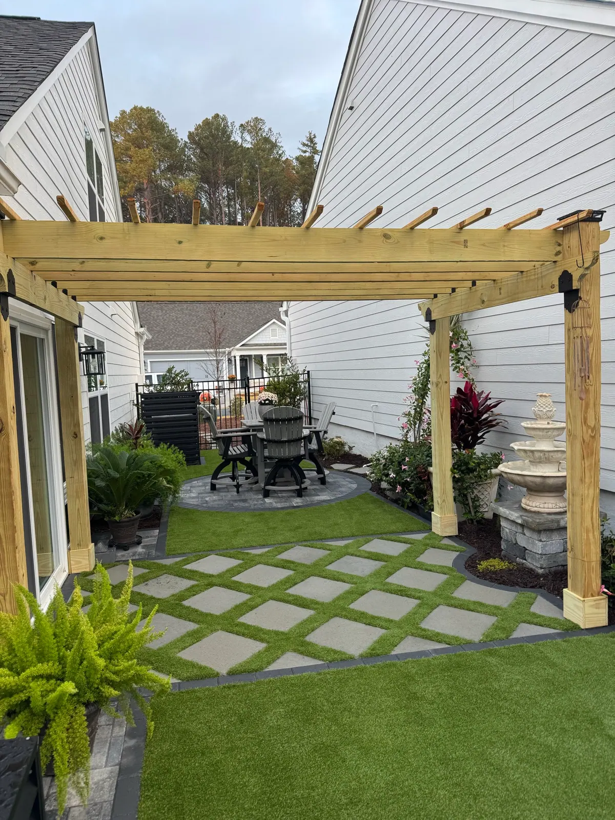 Backyard courtyard with cedar pergola and turf-and-paver lattice at the Howald project by GreenTree Landscapes