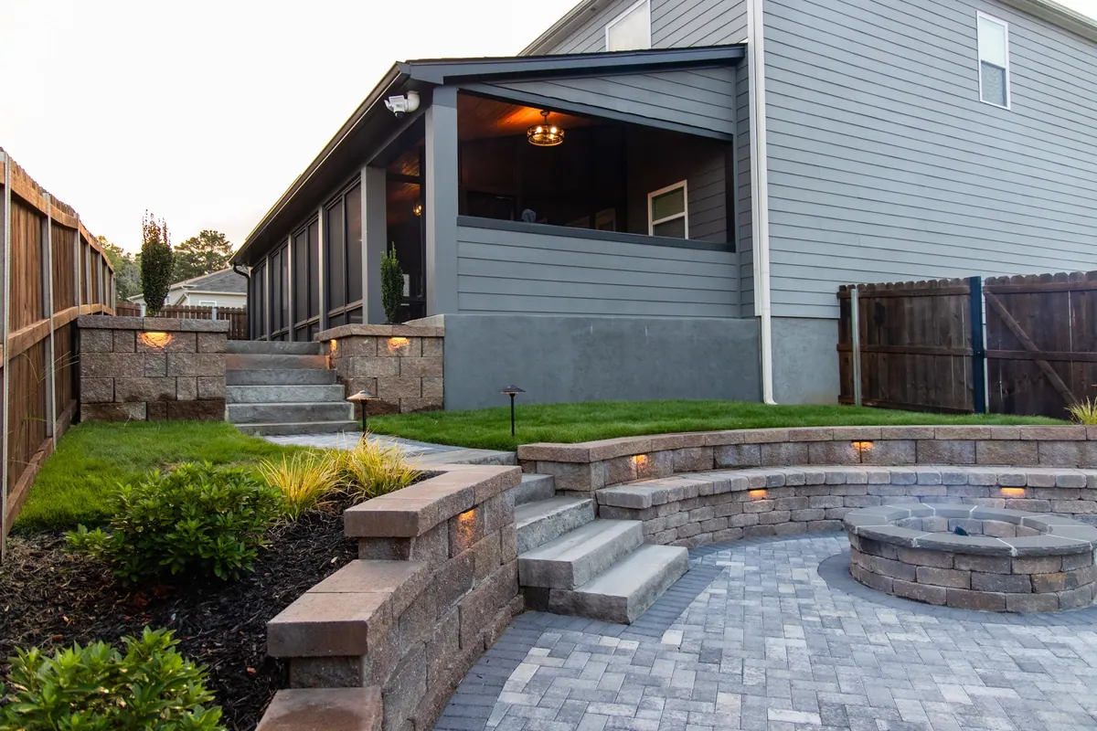 Bluestone patio with sandstone retaining walls at dusk, built by GreenTree Landscapes in the Atlanta metro